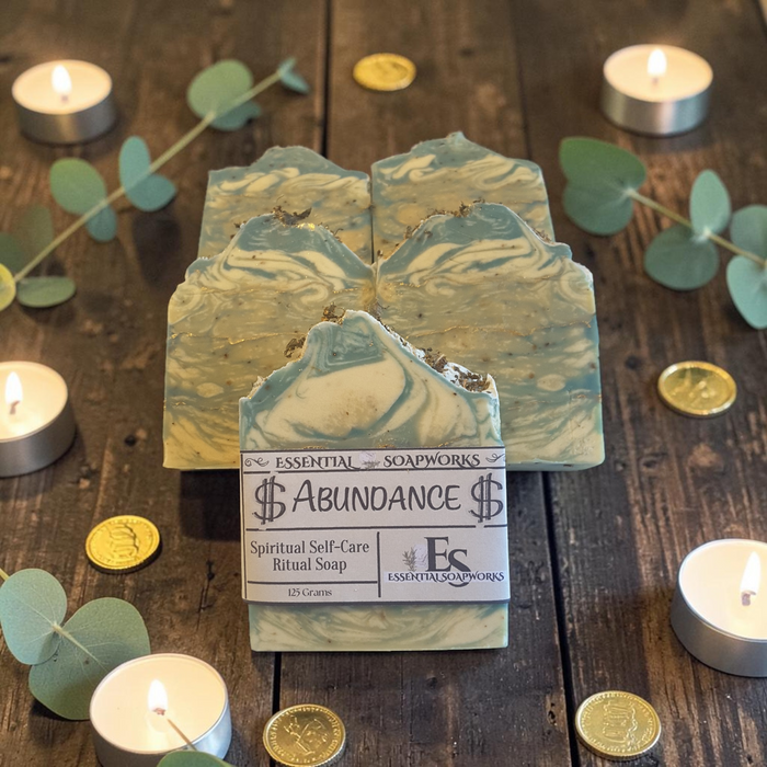 abundance soap on a wooden surface with gold coins and candles in the background