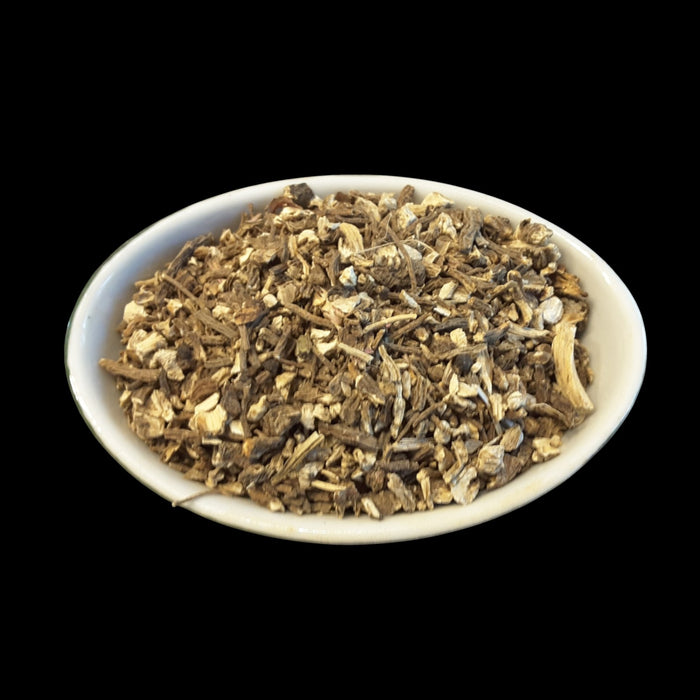 A white oval bowl filled with Angelica Root for witchcraft photographed against a solid black background.