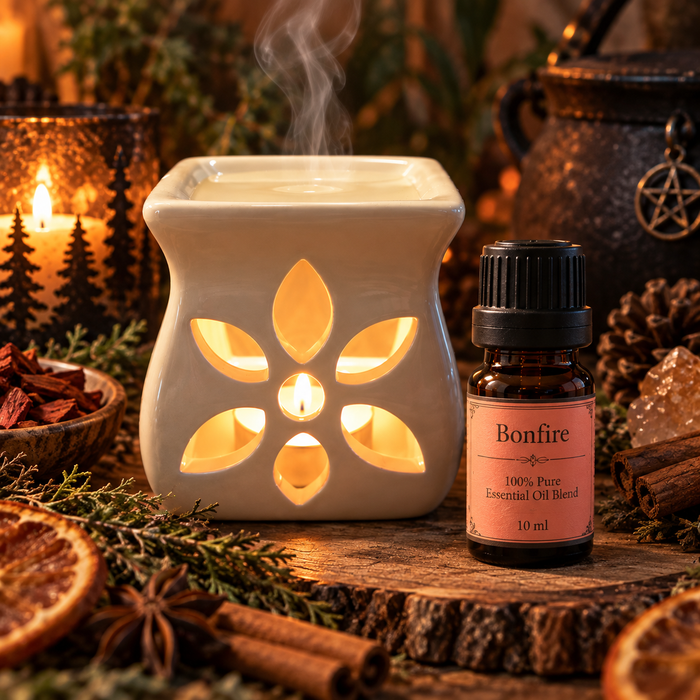 Bonfire witchy diffuser blend alongside an essential oil burner, shown on a wooden surface with cinnamon, anise and orange slices
