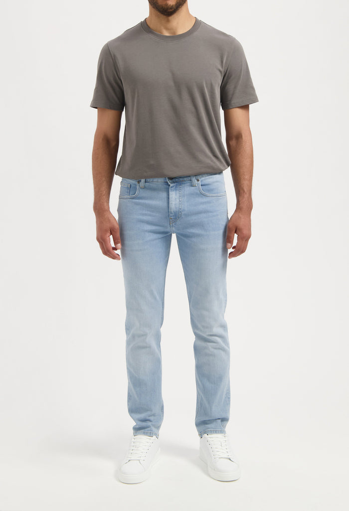 Sustainable MUD Jeans denim shorts in light blue, ethically made from organic cotton, paired with a casual green tee.