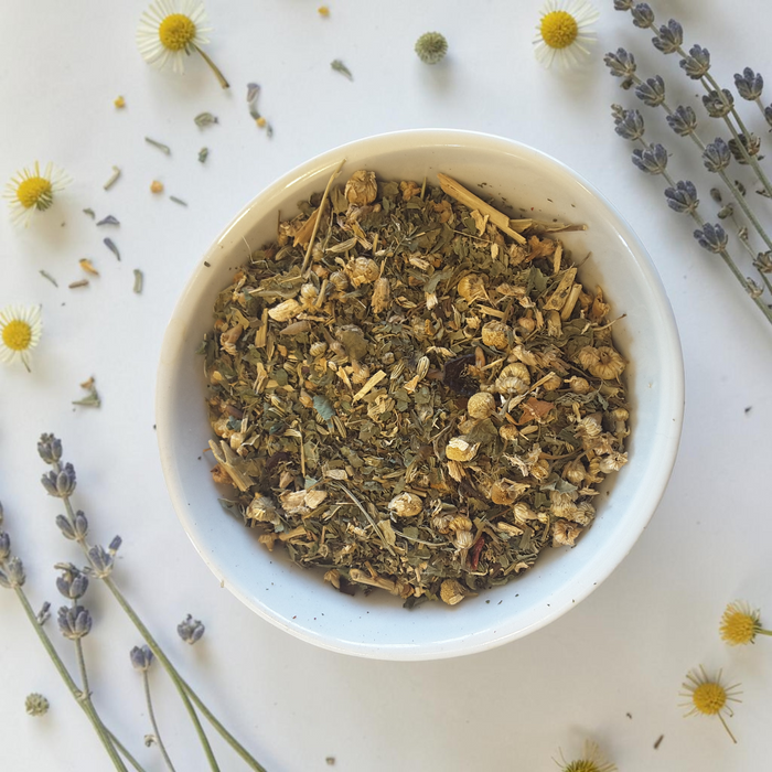 chakra balance loose leaf tea blend on a light surface with lavender and chamomile flowers.