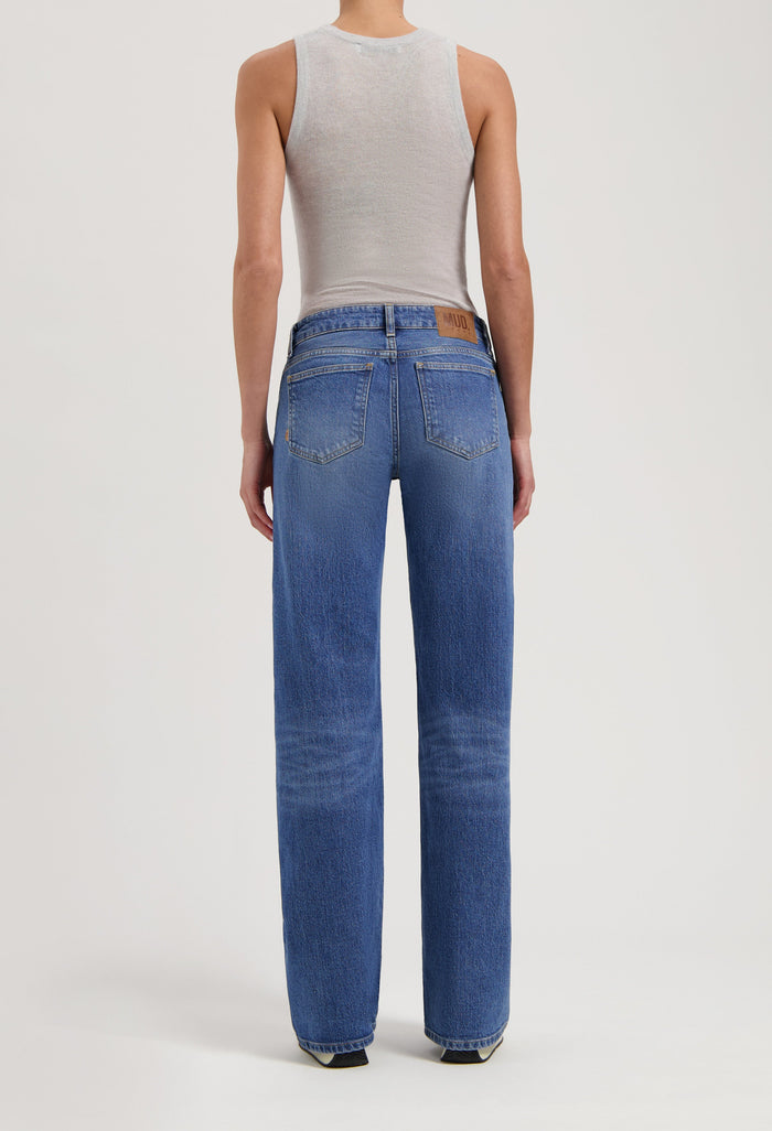 Back view of a person wearing classic blue high-waisted MUD jeans and a light gray sleeveless top, showcasing denim style.