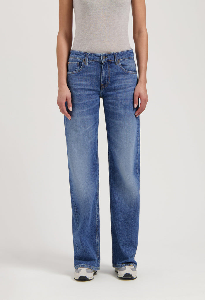 Classic blue straight-leg denim jeans worn with a gray sleeveless top, featuring a comfortable and casual style.