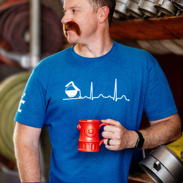 A man wearing the blue Coffee EKG shirt holding a red coffee mug.