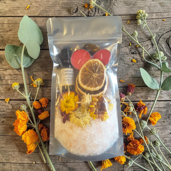 Confidence & Vitality Bath Ritual Kit with tealight candles, flowers, orange slices, tiger's eye crystal and ritual oil on a wooden surface