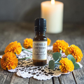 Courage & Confidence Emotional Wellness Oil on a doily on a wooden surface with orange flowers
