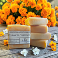 Courage & Confidence emotional balance soap on a wooden surface with flowers in the background.