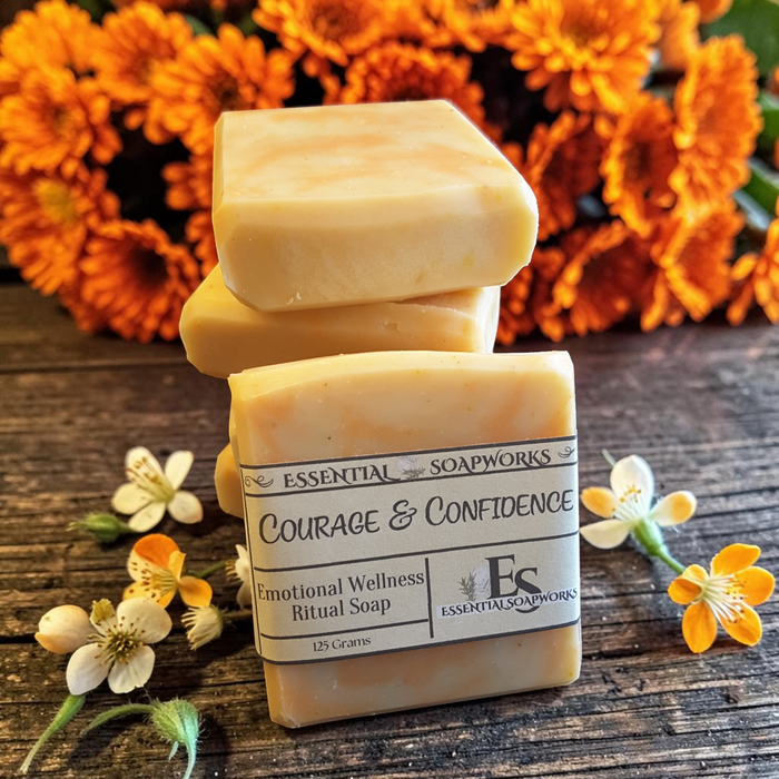 Courage & Confidence emotional balance soap on a wooden surface with flowers in the background.
