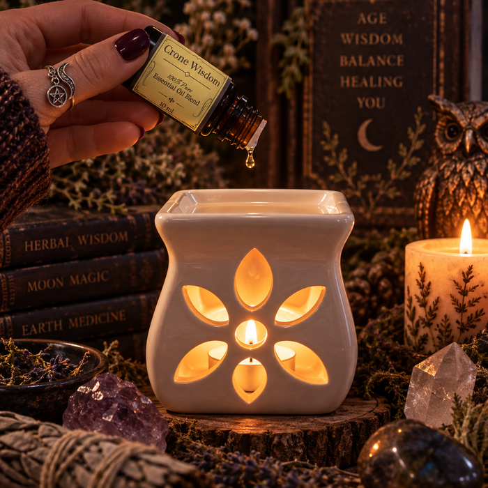 Crone Wisdom witchy diffuser blend being poured into an essential oil burner with a stack of books in the background