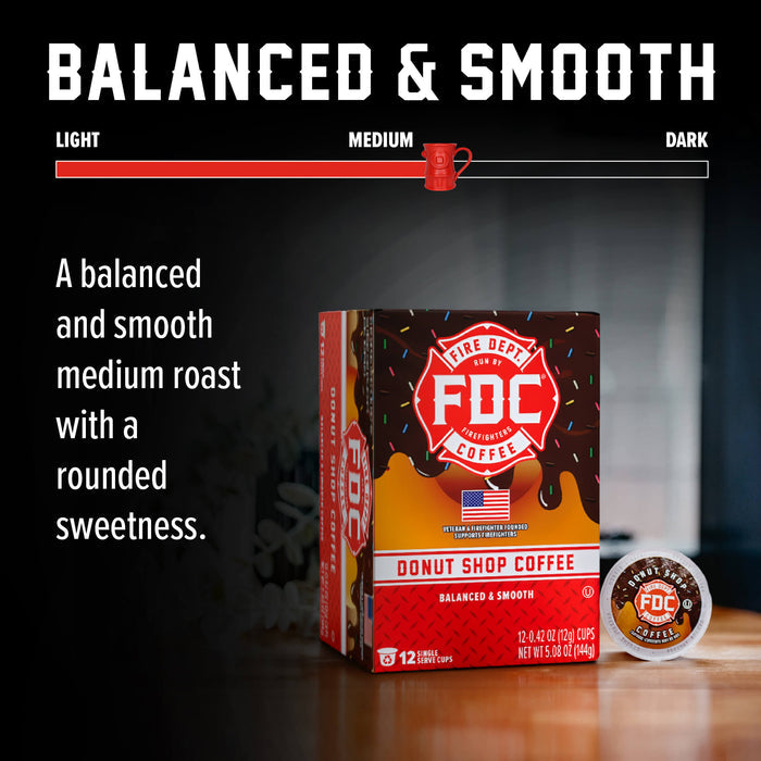 A box of FDC Fire Department Coffee Donut Shop Coffee in the Balanced & Smooth medium roast variety, shown alongside a single coffee capsule on a dark background with marketing text and a roast slider graphic.