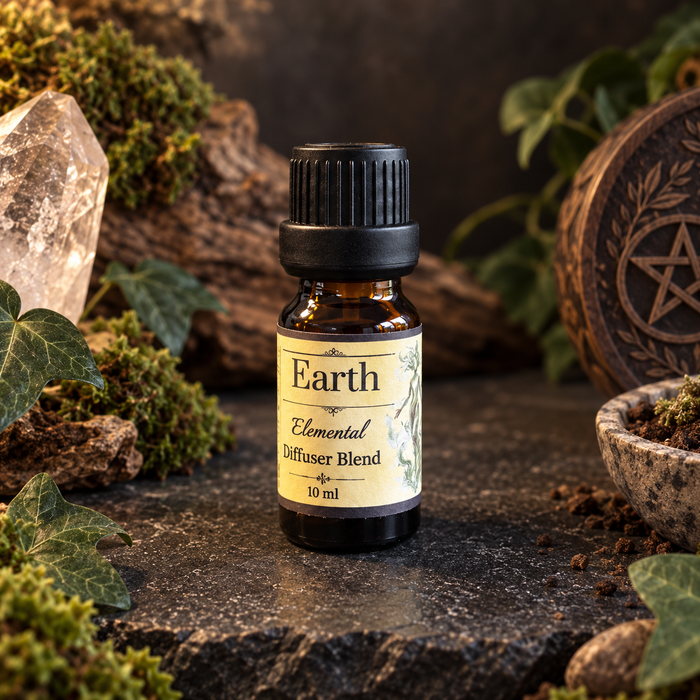 A 10 ml amber glass bottle of Earth Elemental Diffuser Blend with a black cap and cream label, styled on a dark stone surface with moss, ivy, a crystal, and a carved wooden pentacle.