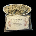 A 30g bag of Eucalyptus dried botanicals from Essential Soapworks, shown in front of a white bowl filled with the same dried leaves, set against a solid black background.