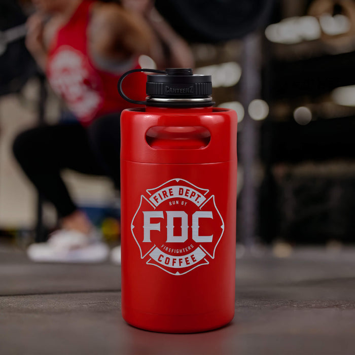 Lifestyle photo featuring a 64oz red stainless steel Fire Department Coffee Growler with Fire Department Coffee logo facing forward.
