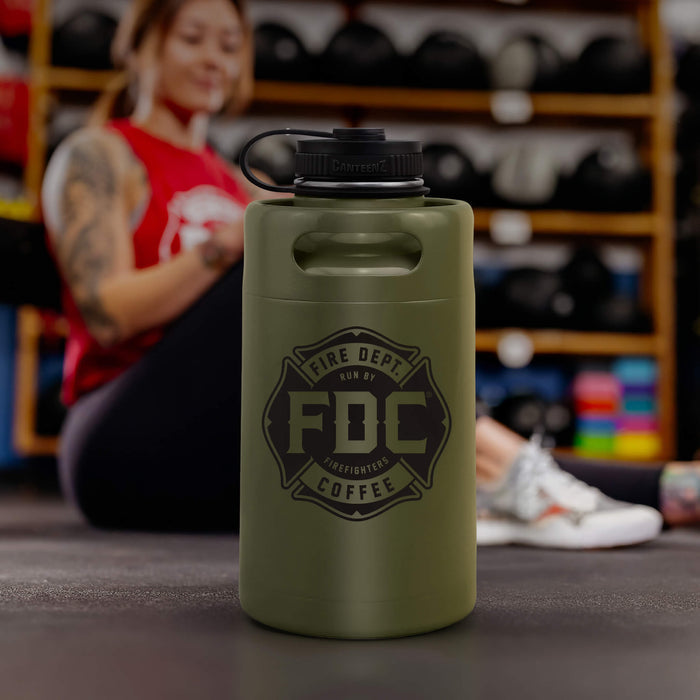 Lifestyle photo featuring a 64oz military green stainless steel Fire Department Coffee Growler with Fire Department Coffee logo facing forward.