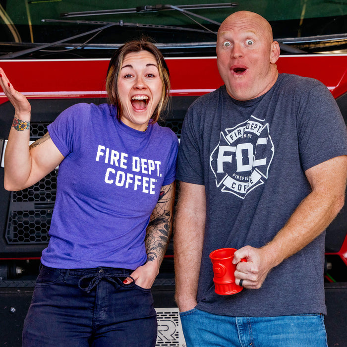 Two people wearing red 'FDC' shirts standing in front of a fire truck.