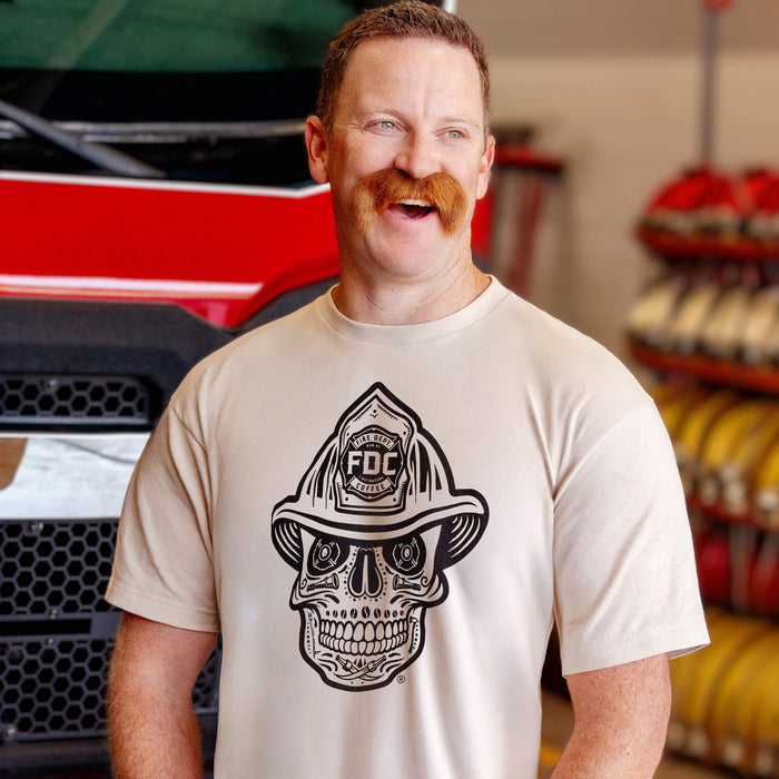 Man wearing a t-shirt with a skull design and 'FDC' logo in a fire station.