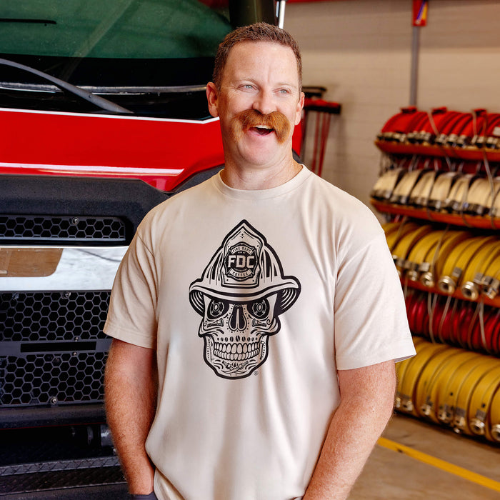 Man wearing a vintage white t-shirt with a black skull design wearing a fire helmet in a fire station