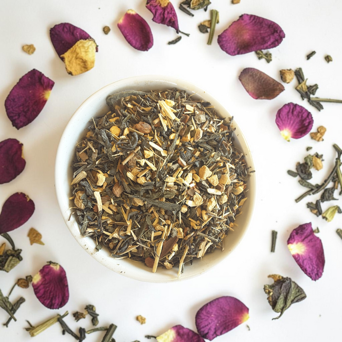 focus loose leaf tea blend in a bowl with purple petals on a white background