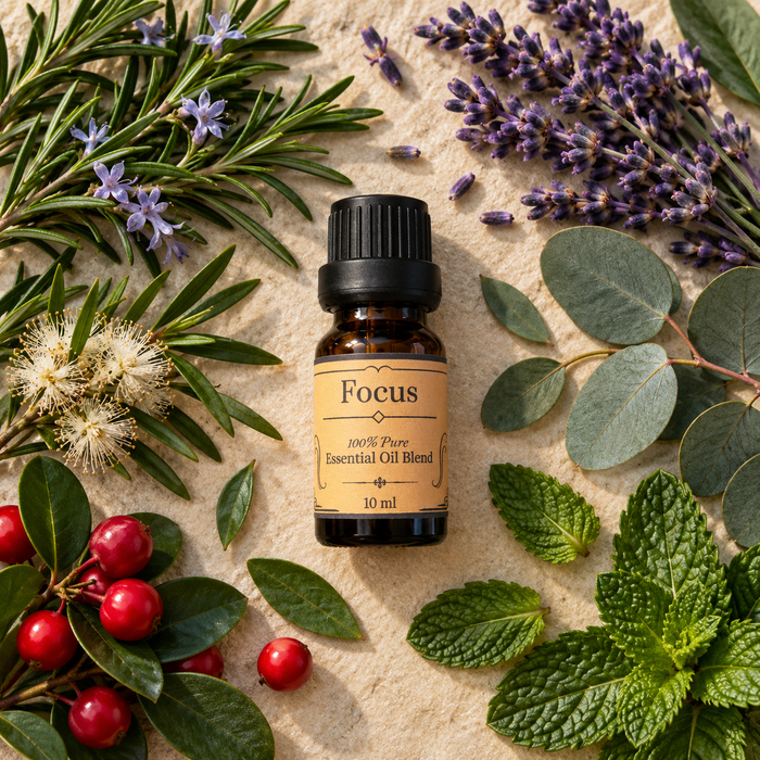 Focus essential oil diffuser blend surrounded by peppermint leaves, lavender and rosemary on a light brown surface
