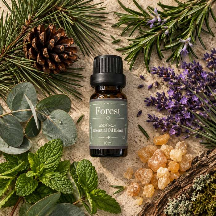 Forest essential oil diffuser blend on a beige surface surrounded by eucalyptus leaves, mint leaves, lavender, rosemary, frankincense resin and pine needles