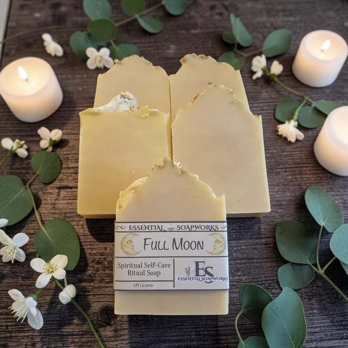 four bars of full moon ritual soap on a dark wooden surface with eucalyptus and candles