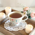 Cup of Gentle Surrender tea on a wooden tray with candles and flowers