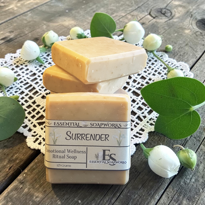 Gentle Surrender Emotional Wellness Soap on a doily on a wooden surface with candles in the background