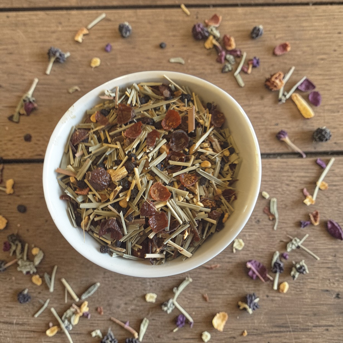Immunity tea blend in a white bowl on a wooden surface.