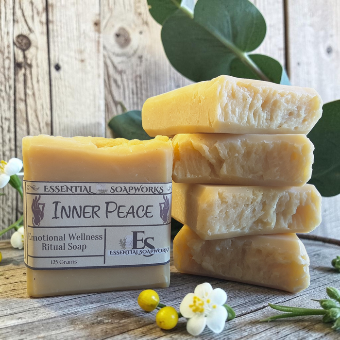 Inner Peace Emotional Wellness Soap on a wooden surface with white flowers and candles in the background.