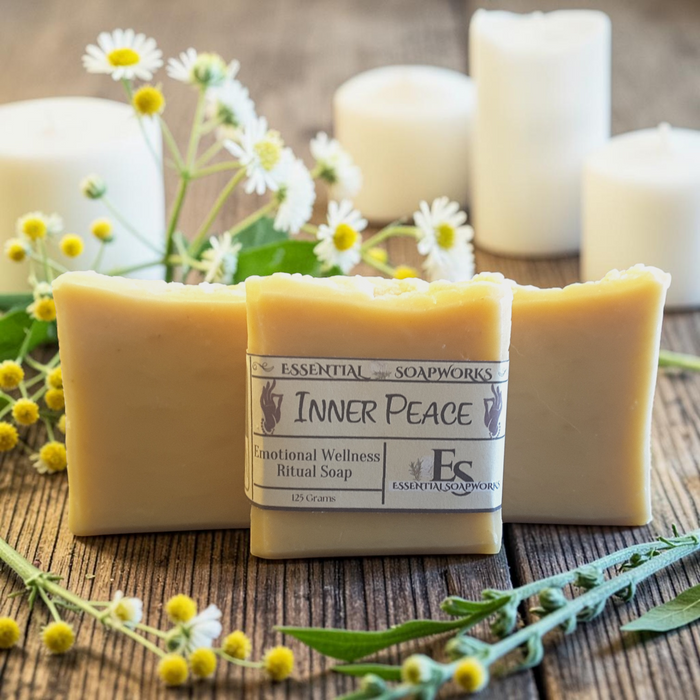 Inner Peace Emotional Wellness Soap on a wooden surface with white flowers and candles in the background.