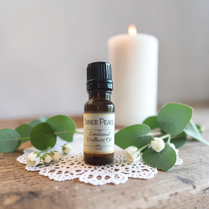 Inner Peace Emotional Wellness Oil on a doily on a wooden surface with greenery and a candle in the background