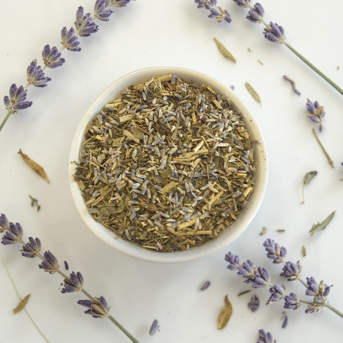 Inner peace loose leaf wellness tea in a white bowl with fresh lavender sprigs on a light background
