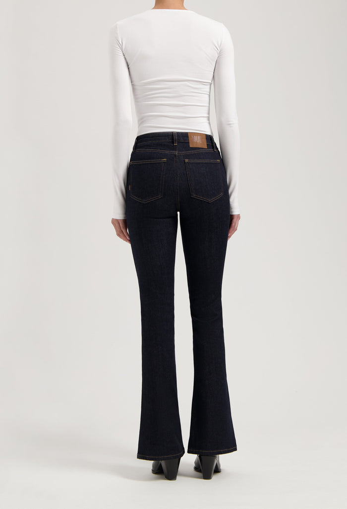 Dark blue flared denim jeans paired with a form-fitting white long sleeve top, highlighting a modern casual style.