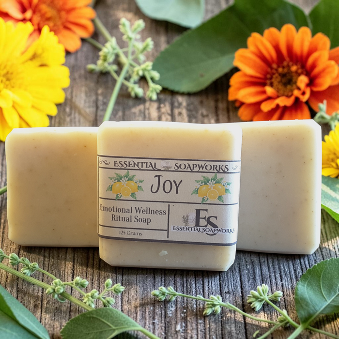Joy Emotional Wellness Soap surrounded by yellow and orange flowers on a wooden surface