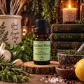 Kitchen Witch essential oil diffuser blend on a wooden surface with peppermint and rosemary with a candle and stack of books in the background