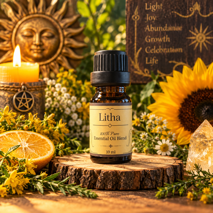 A small amber glass bottle labeled Litha essential oil blend with a black cap, displayed on a wood slice surrounded by flowers, a lit candle, a sun face ornament, and a crystal, in a styled natural setting.