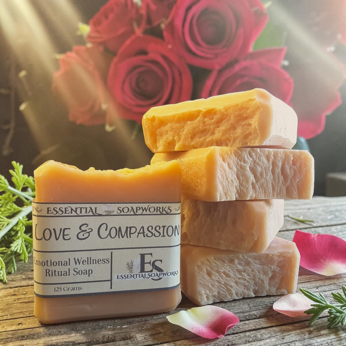 Love & Compassion Emotional Wellness Soap on a wooden surface with red roses in the background.