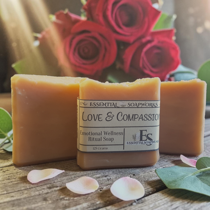 Love & Compassion Emotional Wellness Soap on a wooden surface with red roses in the background.