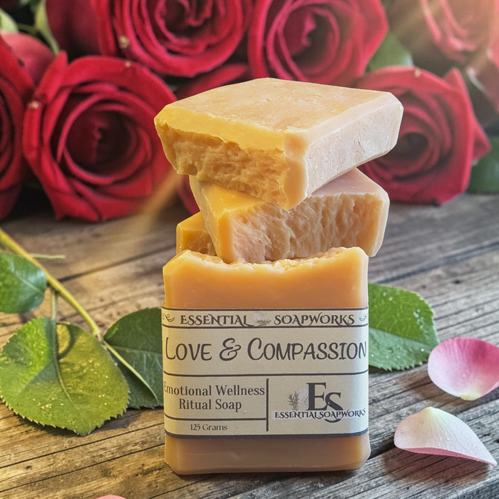 Love & Compassion Emotional Wellness Soap on a wooden surface with red roses in the background.