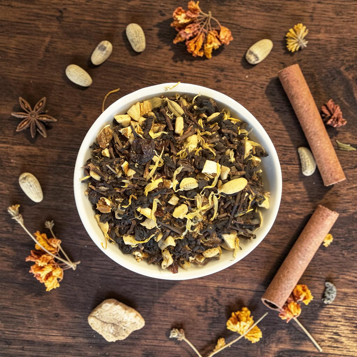 Loose leaf Mabon tea in a dish on a wooden surface with herbs and spices