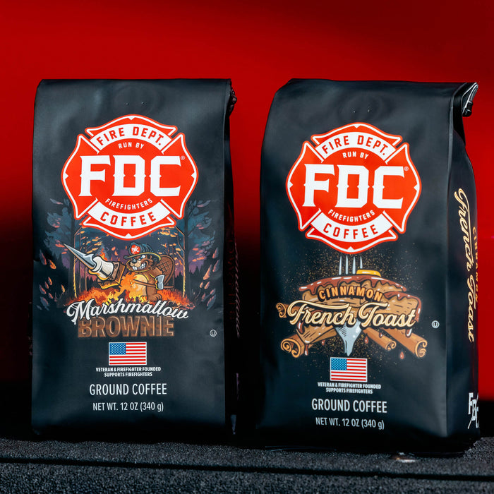 A Marshmallow Brownie Coffee bag and a Cinnamon French Toast Coffee bag on the bumper of a fire truck with a red background.