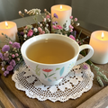 Mindful Presence Emotional Wellness Tea on a doily surrounded by candles and flowers