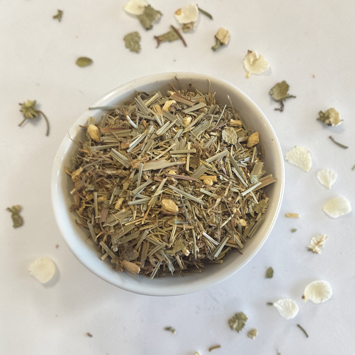 Mindful Presence Emotional Wellness Tea on a light surface with scattered herbs and petals.