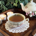 Yerba mate tea in a tea cup with teapot, candles, and flowers on a wooden tray