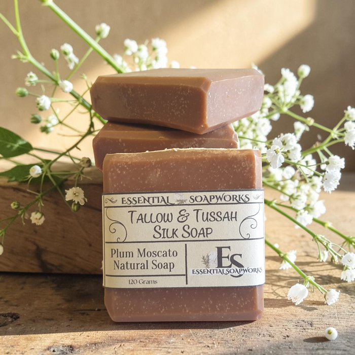 plum scented tallow soap on a wooden surface with white flowers