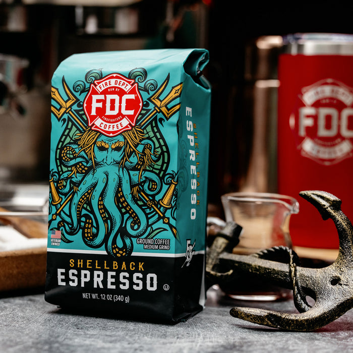 An image of FDC's Shellback Espresso on a table next to a small anchor and coffee brewing items.