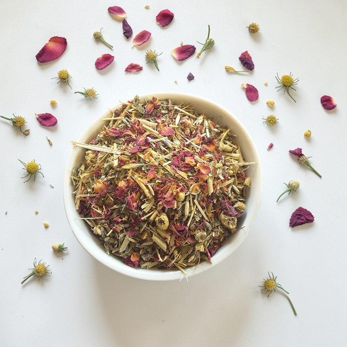 Restoration & Renewal Emotional Wellness Tea on a white background with scattered petals and buds.