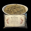 A clear plastic bag of rosemary with a cream label, shown in front of a white bowl filled with dried rosemary on a black background.