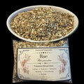A bowl and bag of dried Rue (Ruta graveolens) botanicals for common ritual use, with the brand 'Essential Soapworks' visible on the label.