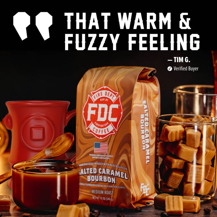 A bag of FDC Fire Department Coffee Salted Caramel Bourbon coffee is displayed in a styled coffee scene with a red mug, a glass of coffee, caramel candies in a glass, and large promotional text reading 'THAT WARM & FUZZY FEELING' by Tim G.